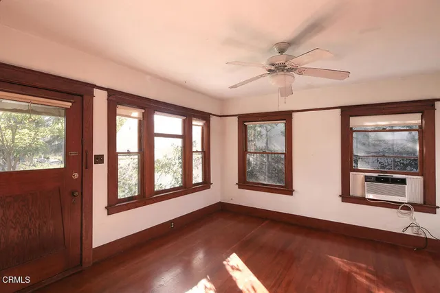 a view of an empty room with window and wooden floor