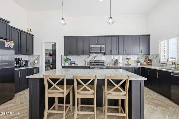 a kitchen with kitchen island granite countertop a sink and a refrigerator
