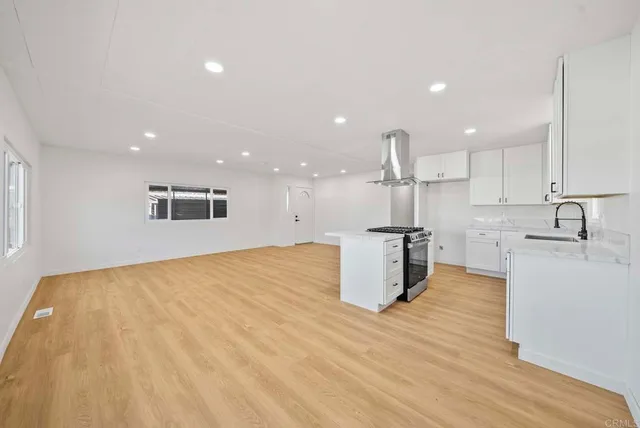 a kitchen with stainless steel appliances granite countertop a sink a stove and a wooden floors