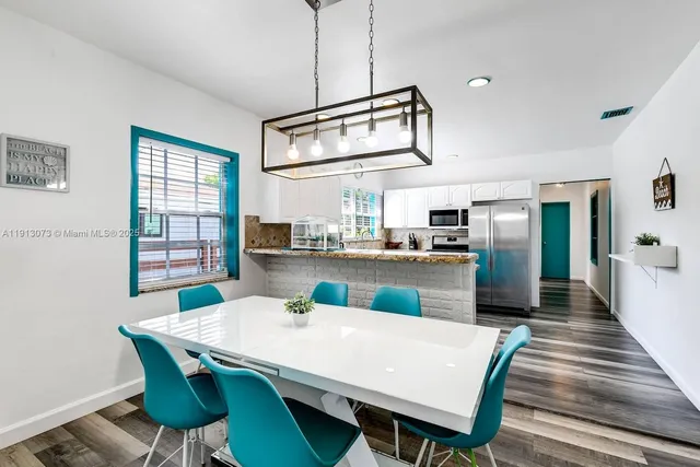 a kitchen with stainless steel appliances granite countertop a dining table chairs and a refrigerator