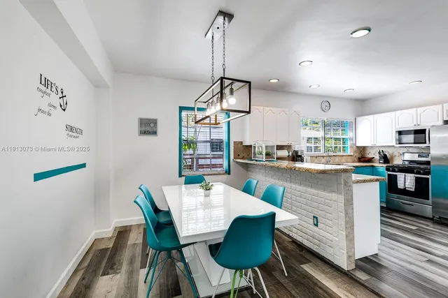 a kitchen with stainless steel appliances granite countertop a sink a stove a dining table and chairs with wooden floor