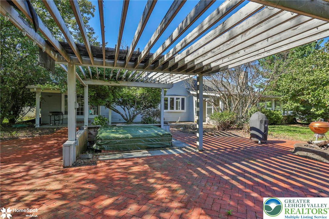 5832 Kernsville Road Orefield, PA 18069 - Photo 42 of 49 A spacious brick patio rests beneath a large wooden pergola in the backyard.