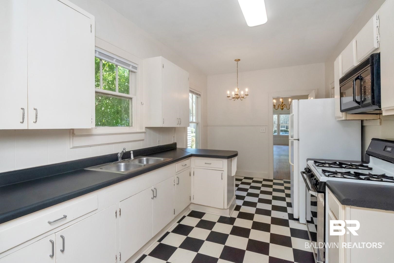 112 South Fulton Street Mobile, AL 36606 - Photo 19 of 35 Kitchen featuring white cabinets, hanging light fixtures, range with gas cooktop, a notable chandelier, and sink
