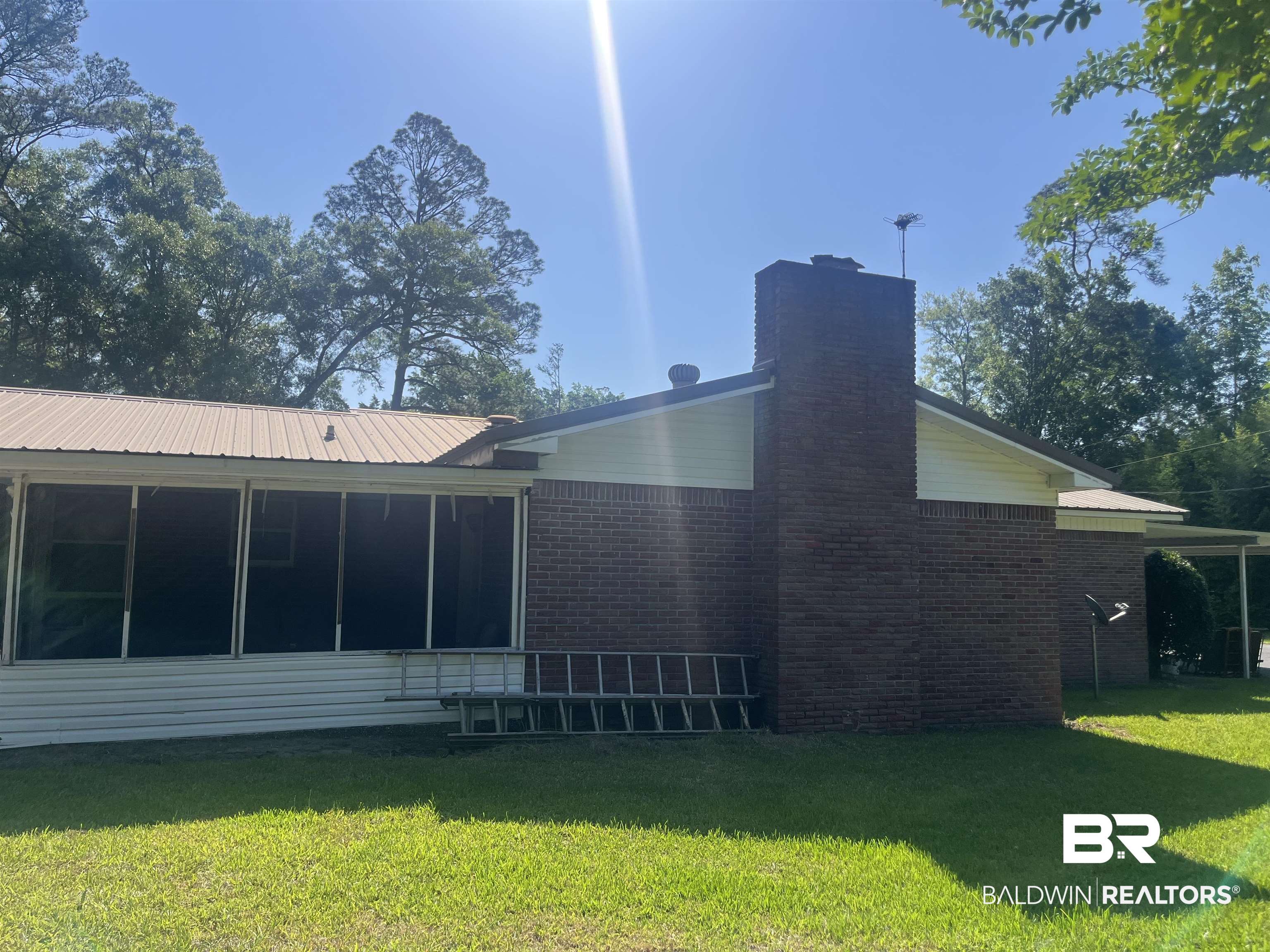 315 Dawkins Road Brewton, AL 36426 - Photo 4 of 19 Rear view of property featuring a chimney, brick siding, a sunroom, and a lawn