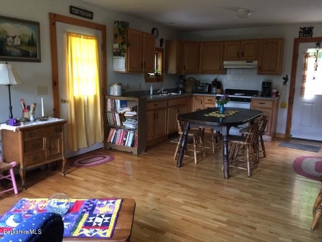 2810 Howe Pond Road Readsboro, VT 05350 - Photo 13 of 29 a kitchen with stainless steel appliances granite countertop a refrigerator a stove a sink dishwasher and a dining table with wooden floor