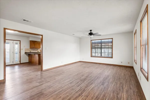 an empty room with wooden floor cabinet and windows