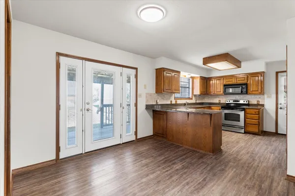 a kitchen with granite countertop a refrigerator and wooden floors