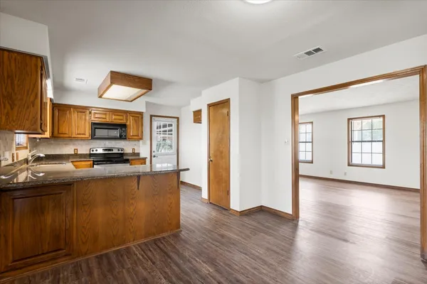 a view of a kitchen with kitchen island a sink wooden floor and a large window