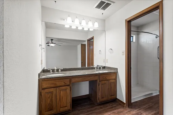 a bathroom with a granite countertop sink a mirror and a shower