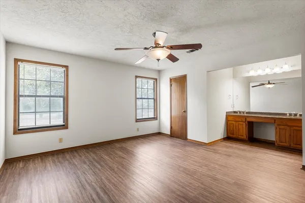 a view of an empty room with window and wooden floor