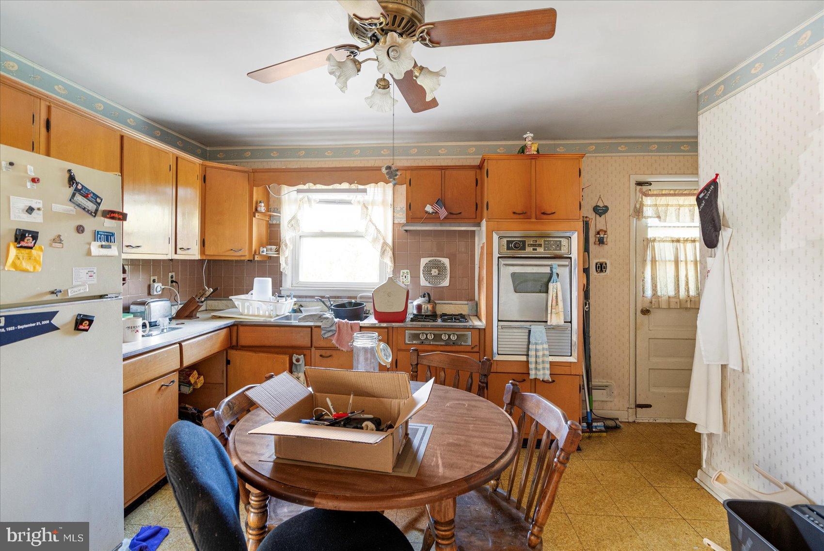 8368 Old Philadelphia Road Baltimore, MD 21237 - Photo 16 of 29 a kitchen with a refrigerator a sink dishwasher a dining table and chairs with wooden floor