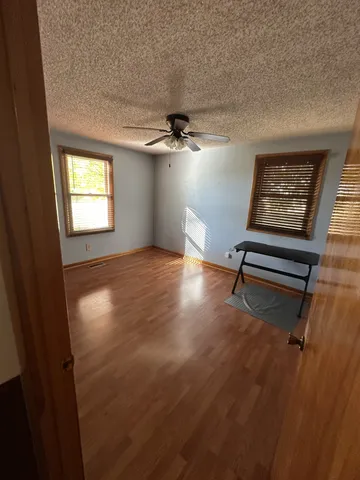 an empty room with windows and fan