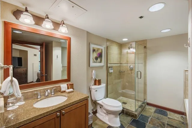 a bathroom with a granite countertop sink toilet a large mirror a shower and a mirror