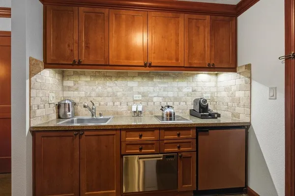 a kitchen with granite countertop stainless steel appliances a sink a refrigerator and cabinets