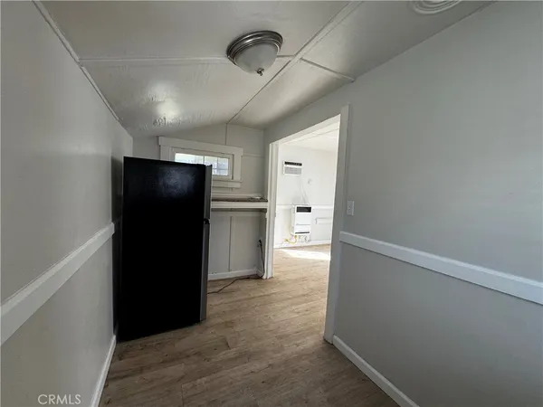 a view of hallway with a refrigerator and wooden floor