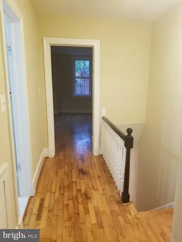 a view of a hallway with wooden floor and stairs