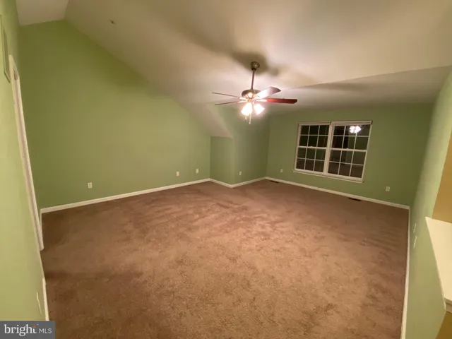 an empty room with windows and ceiling fan