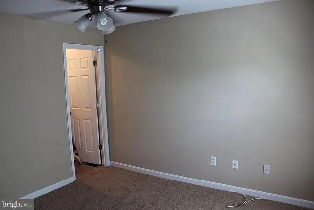 an empty room with a chandelier fan and a window