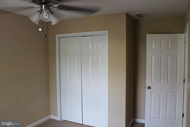 an empty room with windows and fan