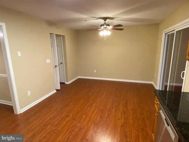 an empty room with wooden floor and chandelier fan