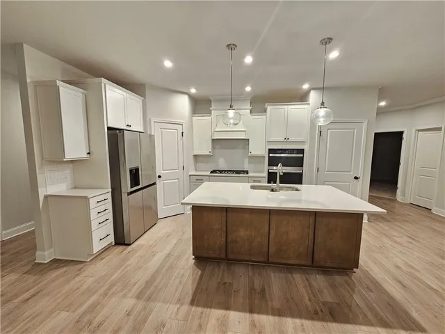 a large kitchen with stainless steel appliances a refrigerator and a stove top oven