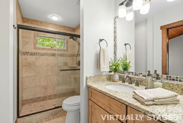 a bathroom with a granite countertop sink a toilet a mirror and shower
