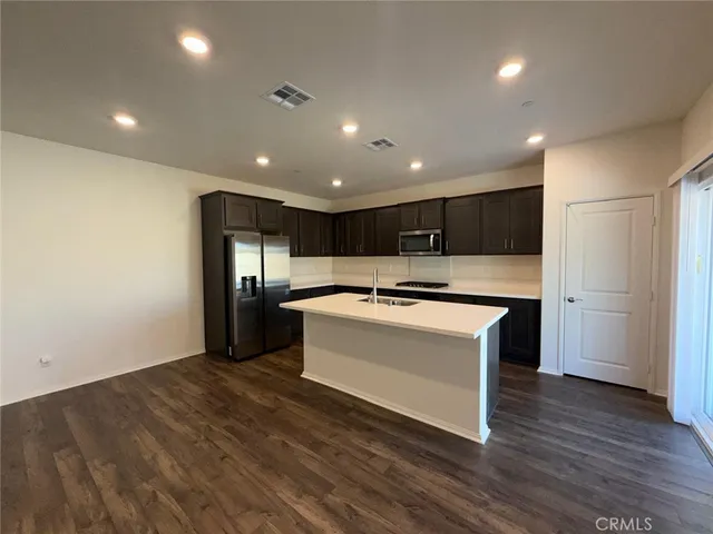 a view of kitchen with stainless steel appliances wooden floor sink and stove