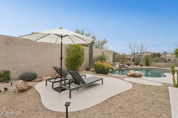 a view of a backyard with couches plants and large trees