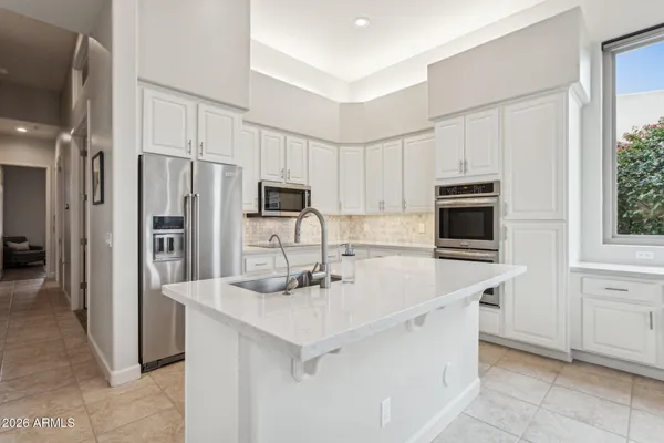 a kitchen with stainless steel appliances a sink a stove a refrigerator with white cabinets