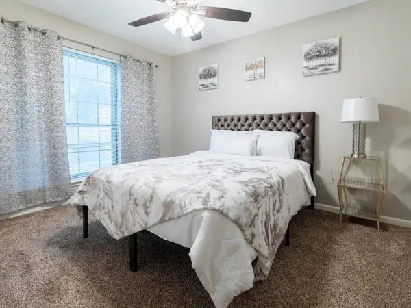 a bed sitting in a bedroom next to a window and a lamp