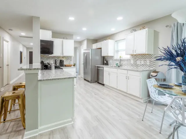 a kitchen with stainless steel appliances kitchen island granite countertop a stove a sink a refrigerator and a microwave