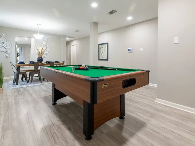a room with pool table windows and wooden floor