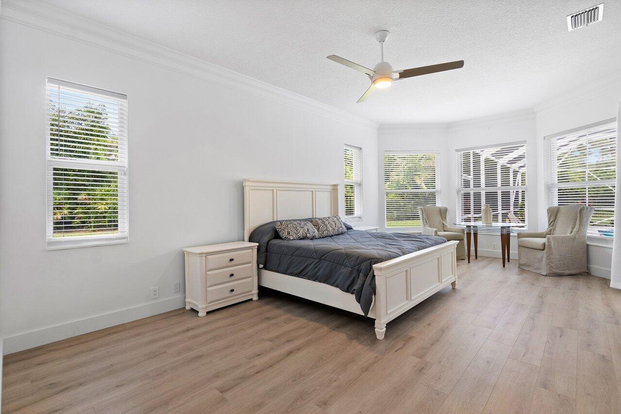 8369 Southeast Island Way Jupiter, FL 33458 - Photo 27 of 41 a bedroom with a large bed and a chandelier