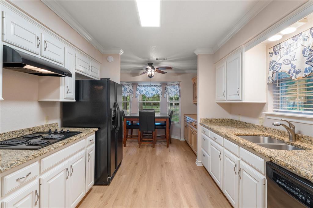 116 Meadowood Road Enchanted Oaks, TX 75156 - Photo 12 of 37 Galley kitchen featuring light wood-finish flooring, white cabinetry, and granite-patterned countertops