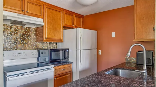 a kitchen with granite countertop a refrigerator and a sink