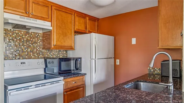 a kitchen with granite countertop a refrigerator and a sink