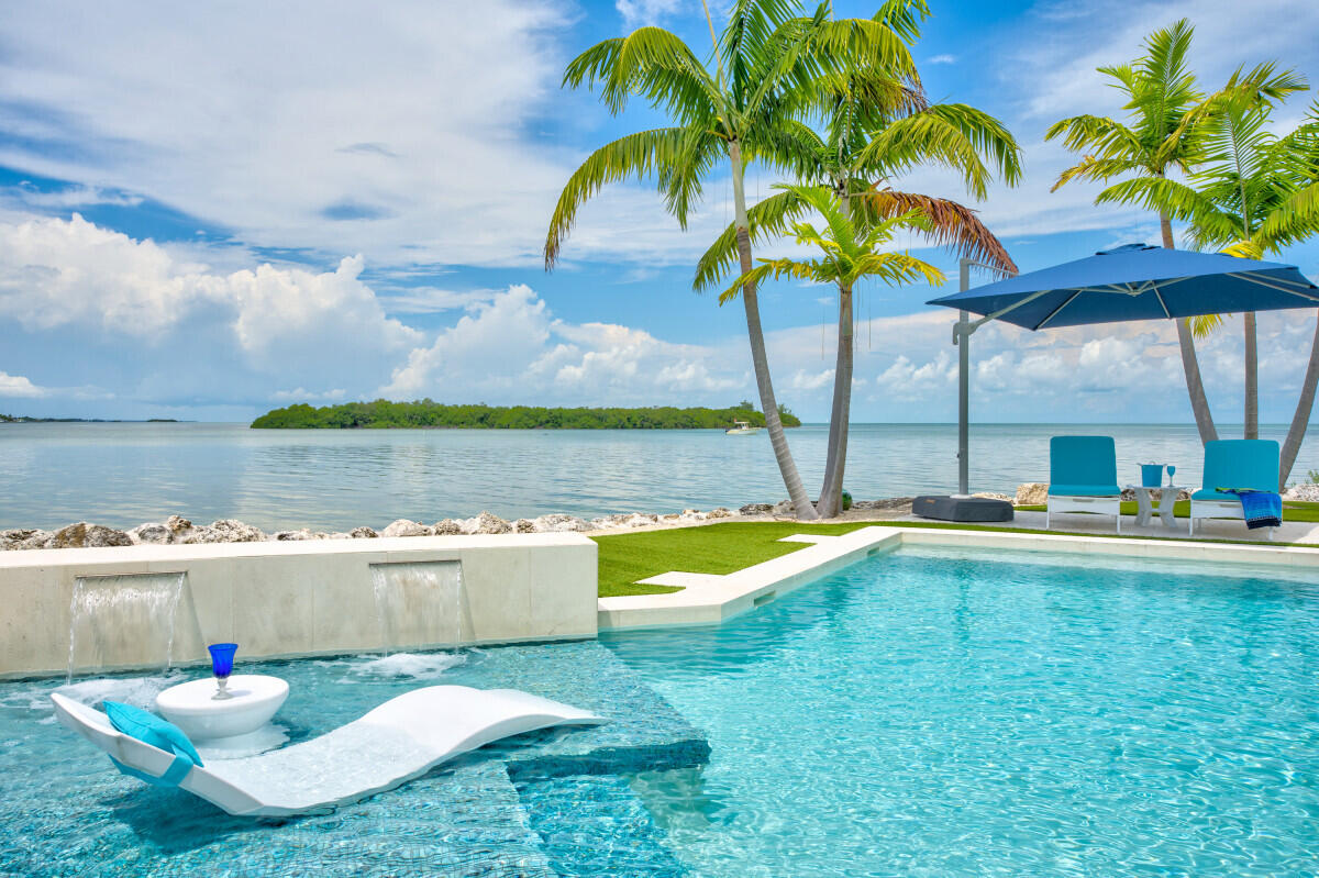 108 Sunset Drive Marathon, FL 33050 - Photo 38 of 46 a view of a swimming pool with a lawn chairs under an umbrella