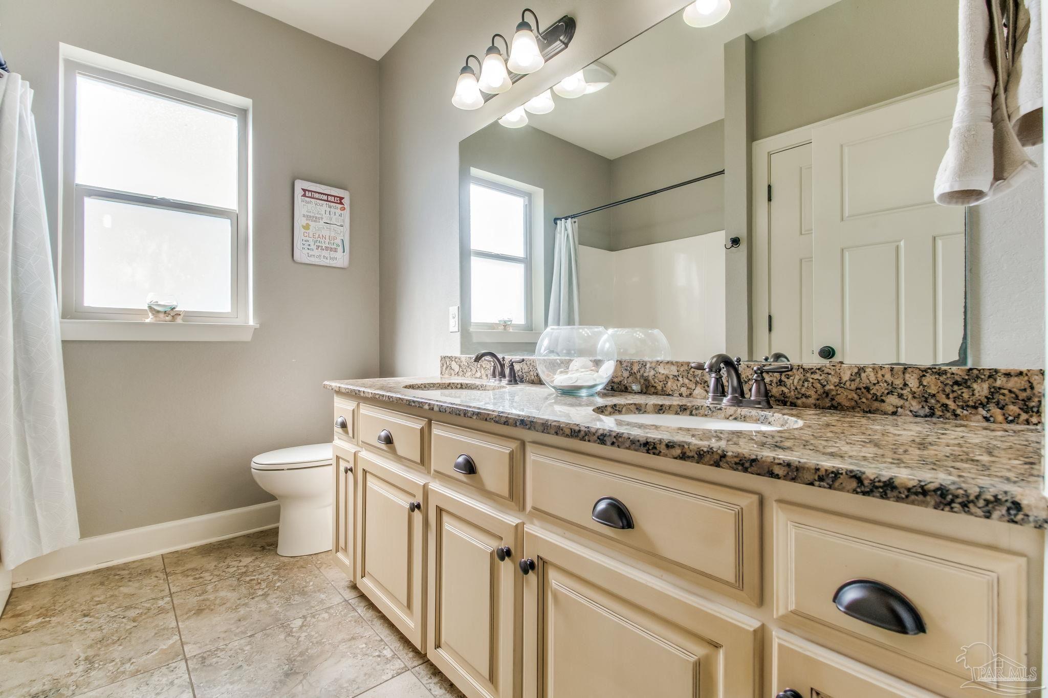 4940 Palmer Ridge Drive Milton, FL 32570 - Photo 35 of 53 a bathroom with a granite countertop sink a toilet and a mirror