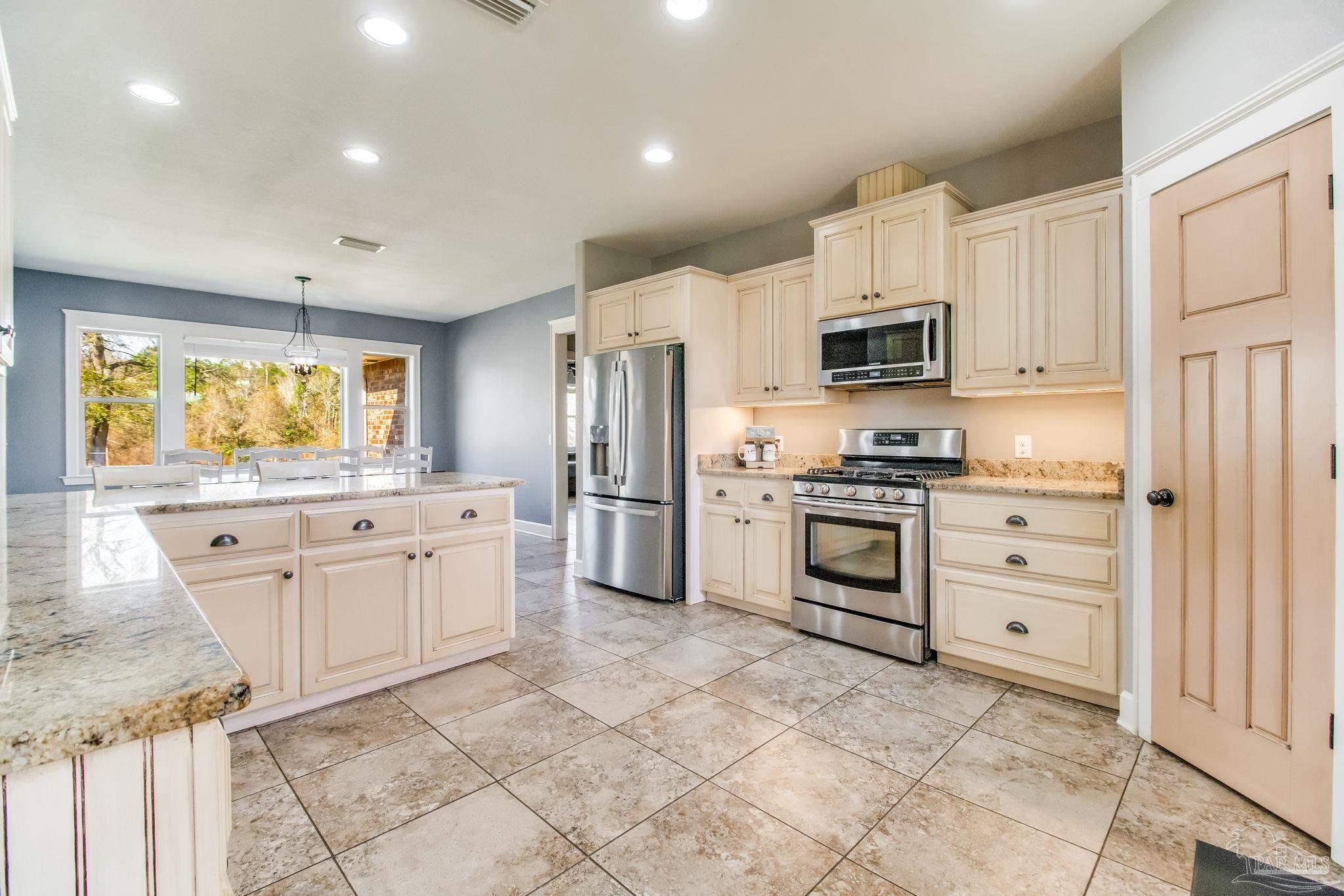 4940 Palmer Ridge Drive Milton, FL 32570 - Photo 4 of 53 a kitchen with white cabinets and stainless steel appliances