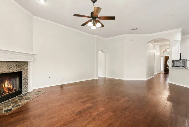 a view of an empty room with wooden floor fireplace and a window