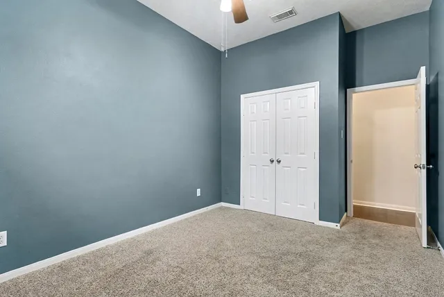an empty room with windows and chandelier fan