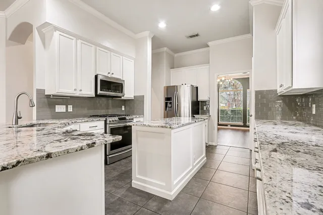 a kitchen with stainless steel appliances granite countertop a stove a sink and white cabinets