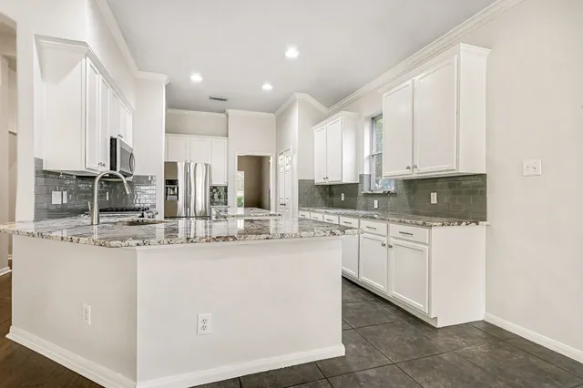 a kitchen with kitchen island granite countertop a stove top oven microwave and refrigerator