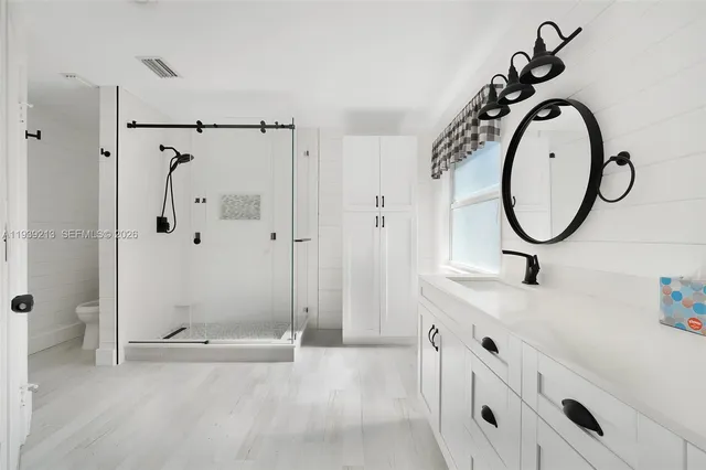 a bathroom with a granite countertop sink a mirror and a shower