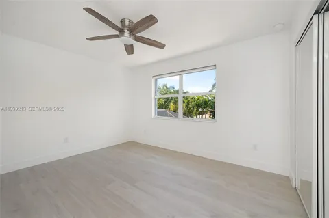 a view of an empty room with window and wooden floor