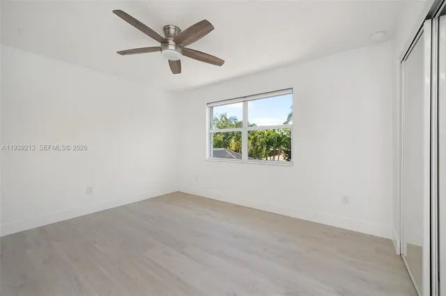 a view of an empty room with window and wooden floor