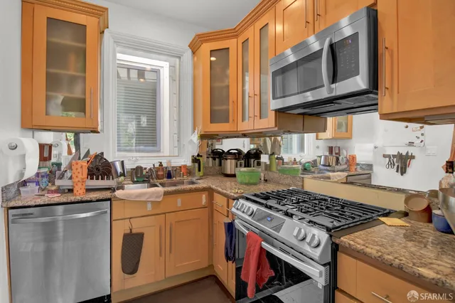 a kitchen with stainless steel appliances granite countertop a stove a sink dishwasher and cabinets with wooden floor