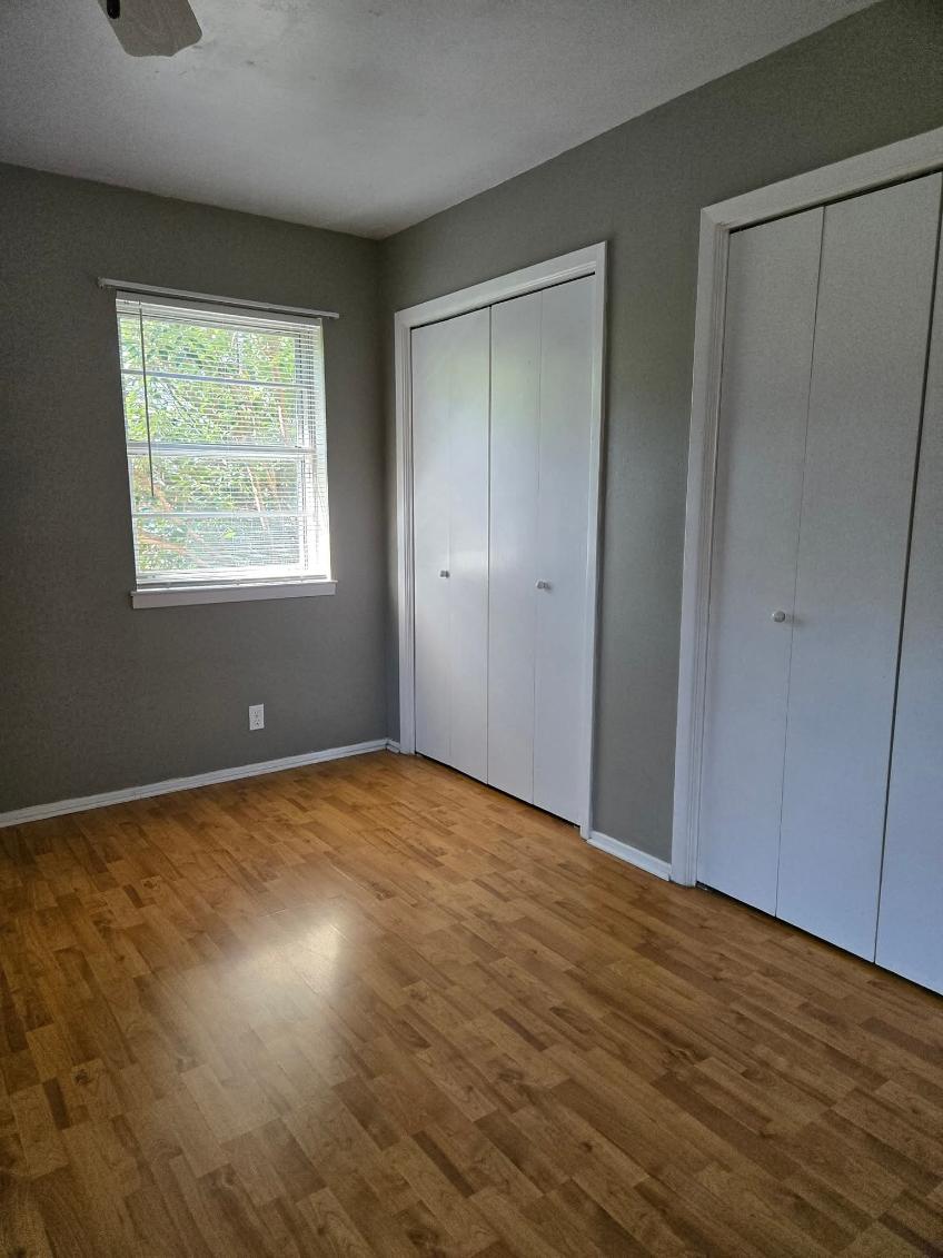 103 Spanish Oak Circle Georgetown, TX 78628 - Photo 11 of 12 Unfurnished bedroom featuring two closets and wood finished floors