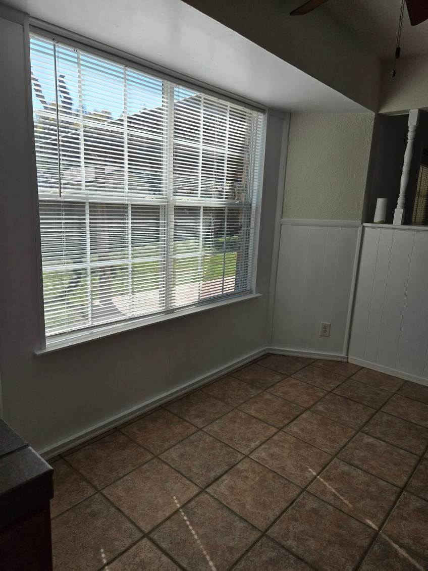103 Spanish Oak Circle Georgetown, TX 78628 - Photo 4 of 12 Spare room with a ceiling fan, a wainscoted wall, and dark tile patterned flooring