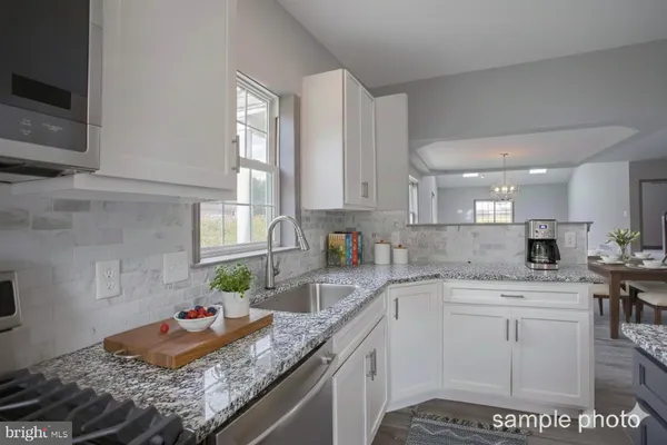 a kitchen with granite countertop stainless steel appliances sink stove and cabinets